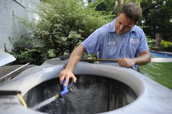 Image of technician performing air conditioner maintenance