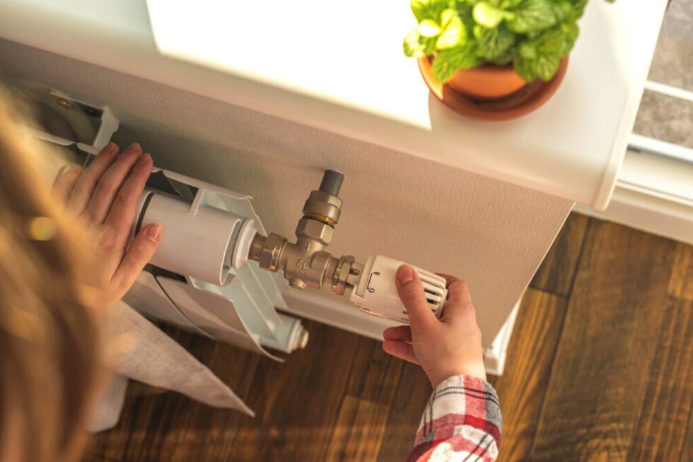 Woman adjusting a valve of her home's heating system - checking for signs of malfunction.